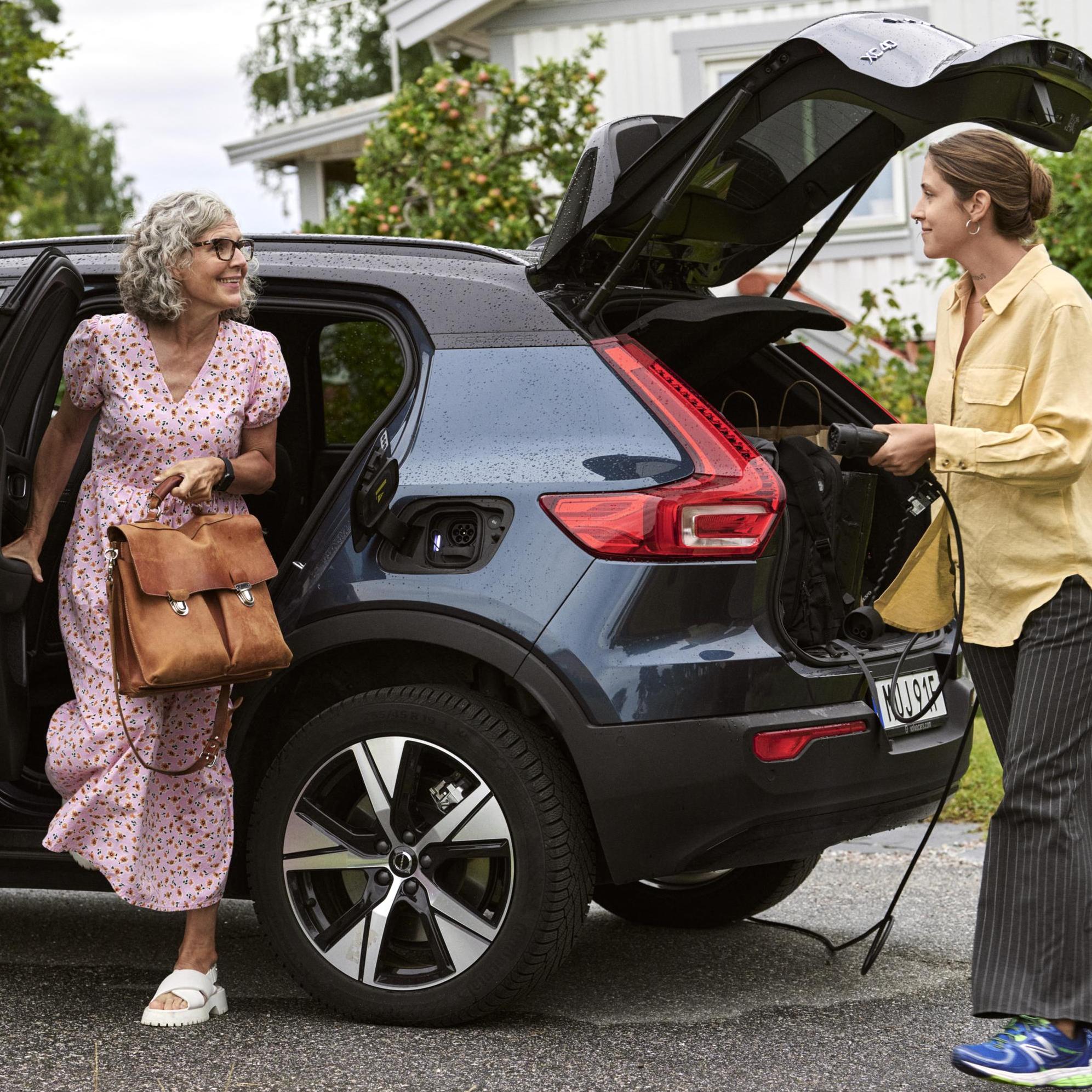 Two women talking to each other while charging the electrical car